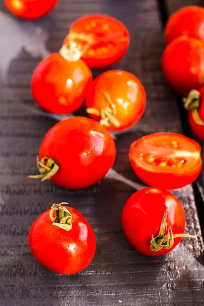 Red juicy tomatoes cherry on dark wooden board — Stock Photo, Image