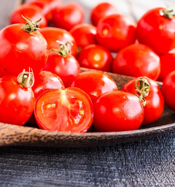 Red juicy tomatoes cherry in brown wooden plate — Stock Photo, Image