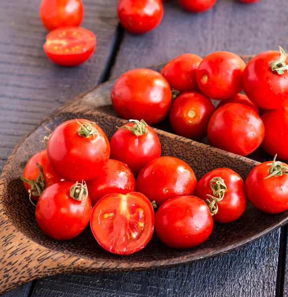 Red juicy tomatoes cherry in brown wooden plate — Stock Photo, Image