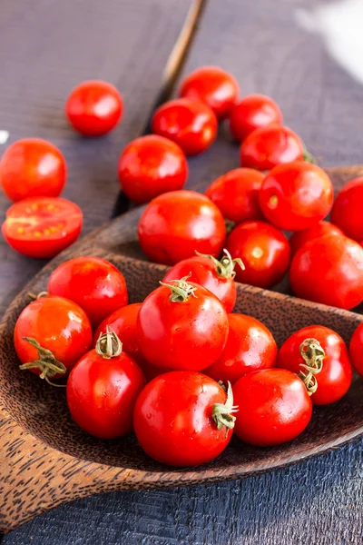 Red  tomatoes cherry in brown wooden plate, vertically — Stock Photo, Image