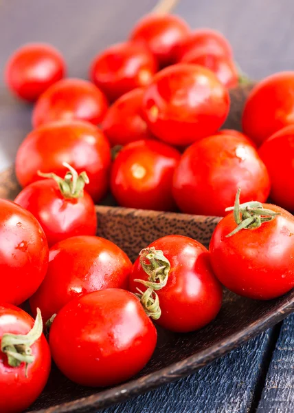 Red juicy tomatoes cherry in brown wooden plate — Stock Photo, Image