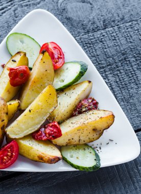 fırında patates ve beyaz tabakta çiğ sebze 