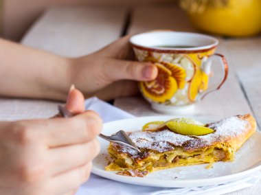 Beyaz bir plaka üzerinde eller elma meyveli turta yemek,