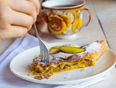 Beyaz bir plaka üzerinde eller elma meyveli turta yemek,