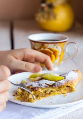 Beyaz bir plaka üzerinde eller elma meyveli turta yemek,