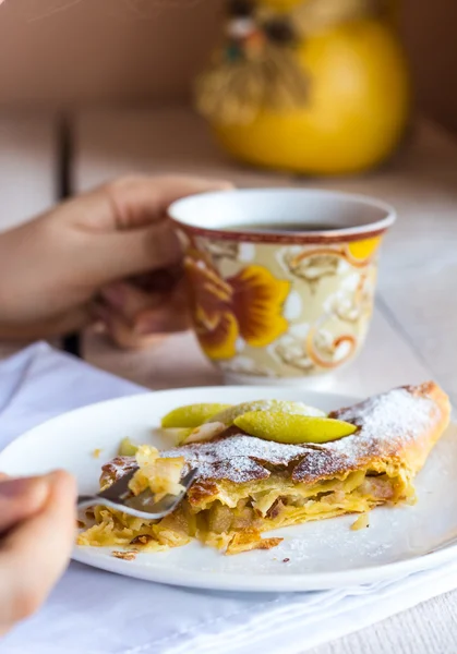 Manger strudel pomme sur une assiette blanche, les mains , — Photo