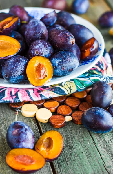 Sappige blauwe pruim plakjes op een houten bord, verticaal — Stockfoto