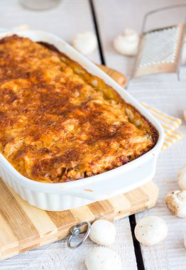 bir kara tahta üzerinde beyaz bir kase mantar eti lazanya 