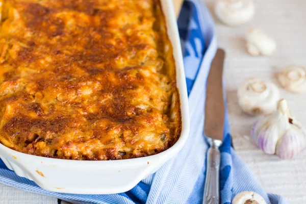 Meat lasagna with mushrooms in a white bowl on a blackboard — Stock Photo, Image