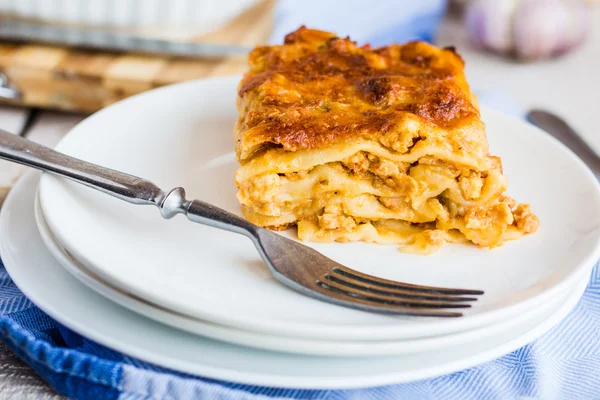 Trozo de lasaña de carne con setas en un plato, cubiertos —  Fotos de Stock