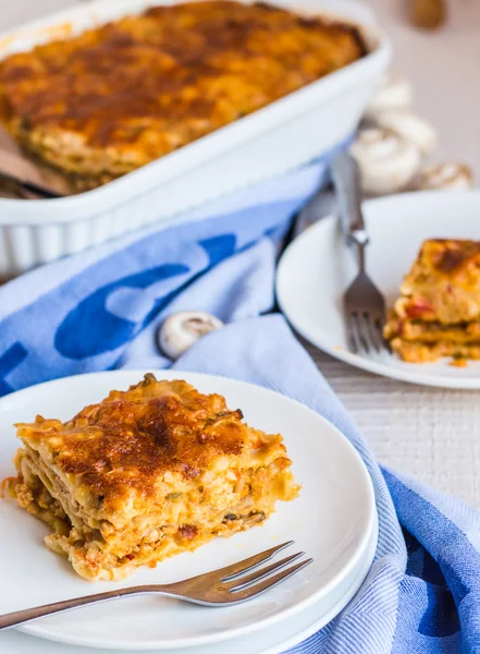 Jí kus masa lasagne s houbami, modrý ručník — Stock fotografie