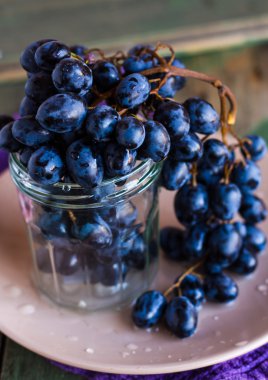 dikey bir cam tabakta, mavi üzüm dal