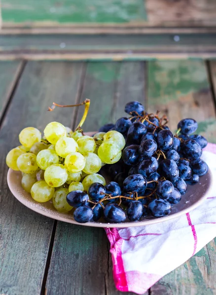 Söta gröna och blå druvor på en tallrik — Stockfoto