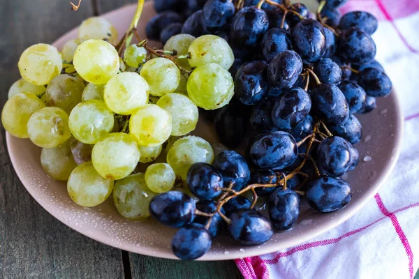 Uvas verdes e azuis doces em um prato, close-up — Fotografia de Stock