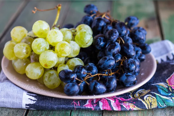 Galho de uvas verdes e azuis em um prato — Fotografia de Stock