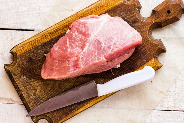 Carne di maiale cruda su tagliere, coltello — Foto Stock