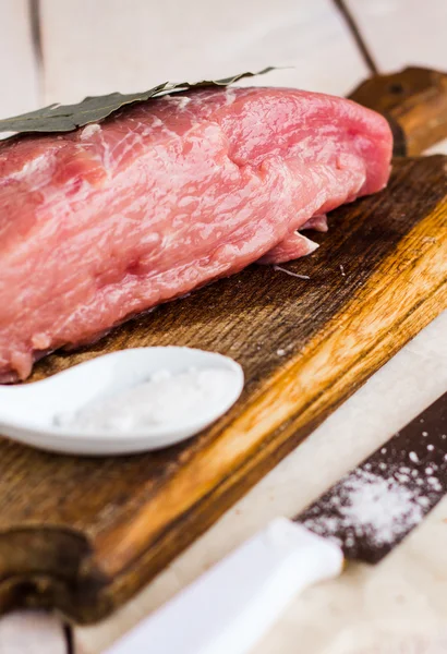 Bit av griskött på en skärbräda, ett lagerblad — Stockfoto