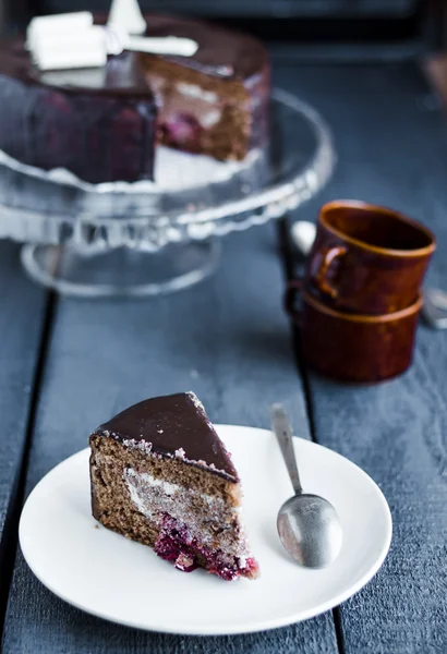 Bit av chokladkaka med grädde och körsbär på vit platta — Stockfoto