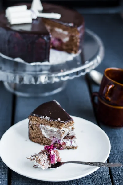 Äta med en sked choklad tårta med smörkräm och körsbär — Stockfoto