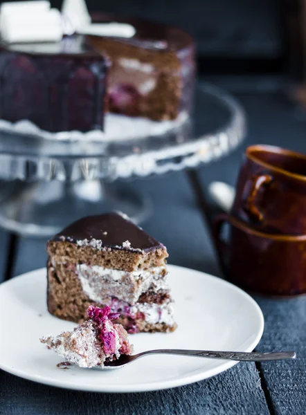 Eat with a spoon chocolate cake with butter cream and cherries — Stock Photo, Image