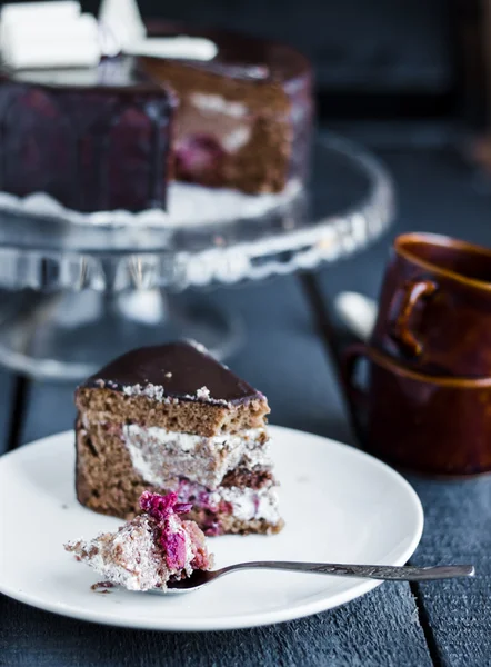 Manger avec une cuillère gâteau au chocolat avec crème au beurre et cerises — Photo