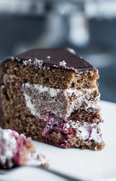 Äta choklad kaka med grädde och körsbär på vit platta — Stockfoto