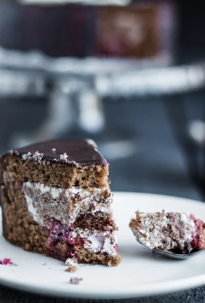 Comer bolo de chocolate com creme e cereja no prato branco — Fotografia de Stock