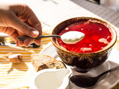 Ukraynalı borscht kırmızı, bir çay kaşığı ekşi krema, el içinde