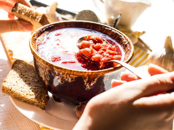 Il processo di mangiare borscht rosso con panna acida, mano, ceramica — Foto Stock
