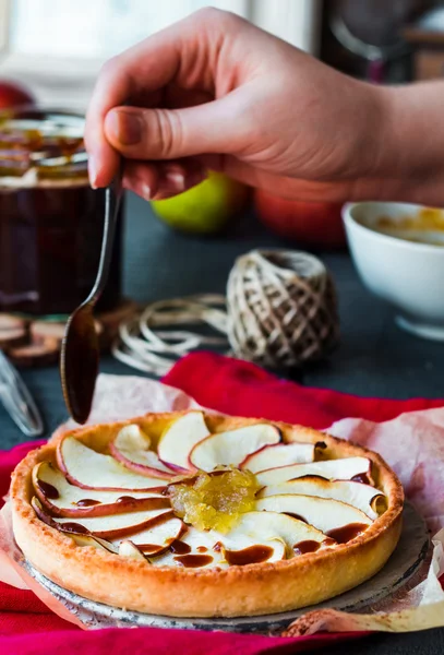 Tartă de mere cu gem de pere se toarnă caramel, mâini — Fotografie, imagine de stoc