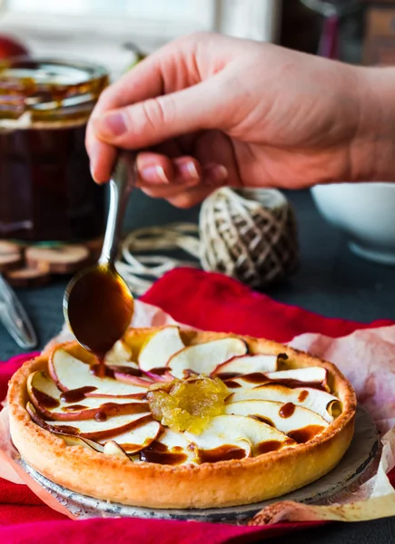 Tartă de mere cu gem de pere se toarnă caramel, mâini — Fotografie, imagine de stoc
