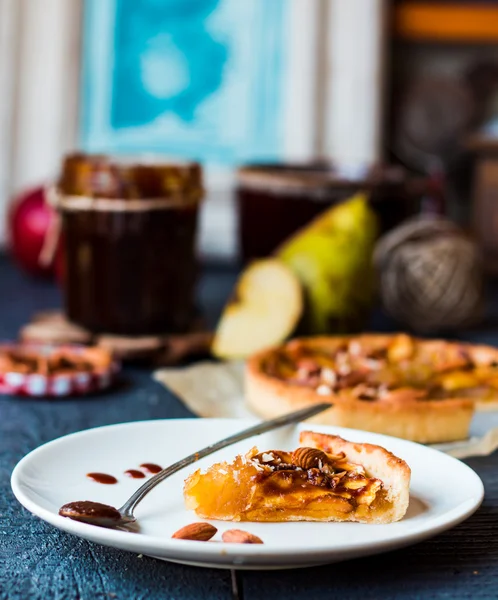 Кусочек яблочного пирога на круглой тарелке, ложка карамели — стоковое фото