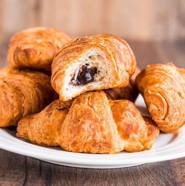 Beyaz bir tabağa kruvasan ile çikolata ısırmak