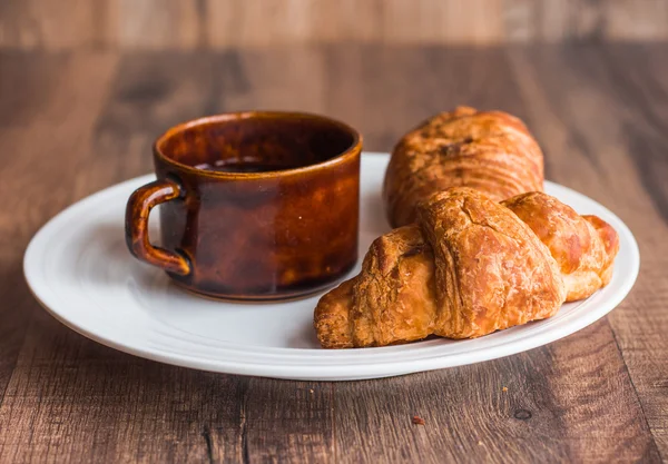 Croissant con chocolate en un plato blanco, una taza de café — Foto de Stock