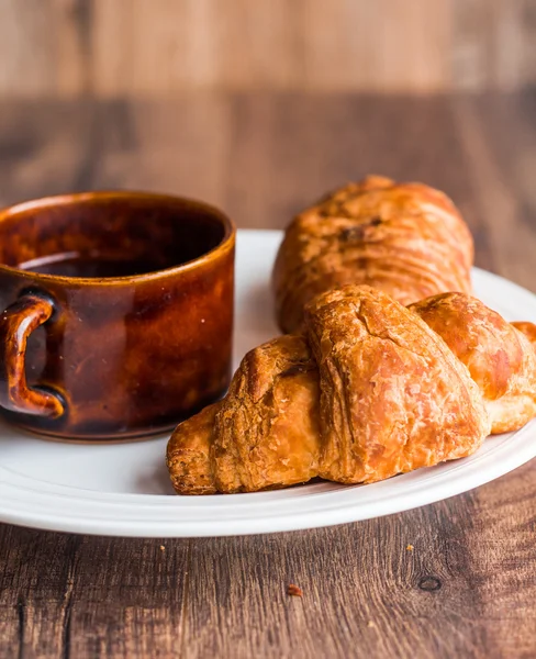 Croissant con chocolate en un plato blanco, una taza de café — Foto de Stock