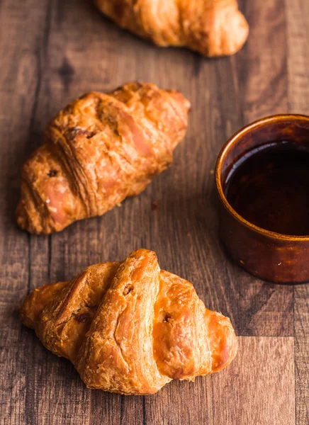 El croissant con el chocolate a la tabla de madera, el desayuno — Foto de Stock