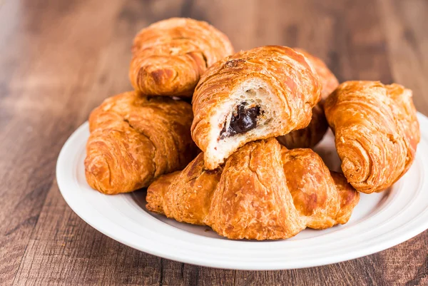 Morder croissants con chocolate en un plato blanco, desayuno — Foto de Stock