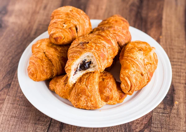 Croissants mordida con chocolate en un plato blanco — Foto de Stock