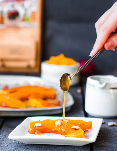 Лейте мёд на ложку запечённой тыквы с грецкими орехами — стоковое фото