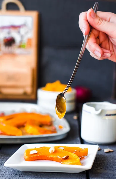 Baked pumpkin with cinnamon and nuts on a plate, hands — Stock Photo, Image