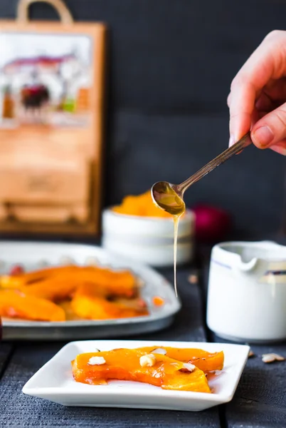 Лейте мёд на ложку запечённой тыквы с грецкими орехами — стоковое фото