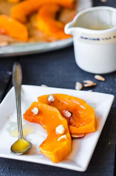 Baked pumpkin slices with cinnamon and nuts, spoon with honey — Stock Photo, Image