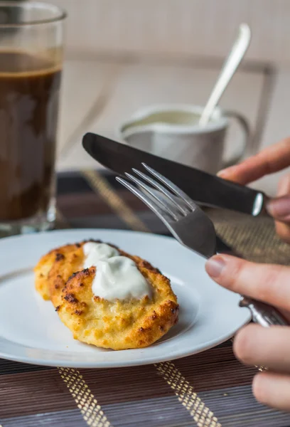 eat curd cheese pancakes with sour cream for breakfast, hands