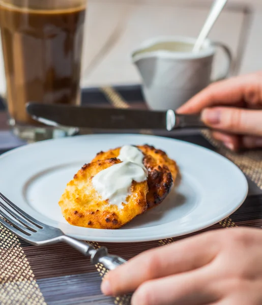 Eten kwark pannenkoeken met zure room voor het ontbijt, handen — Stockfoto