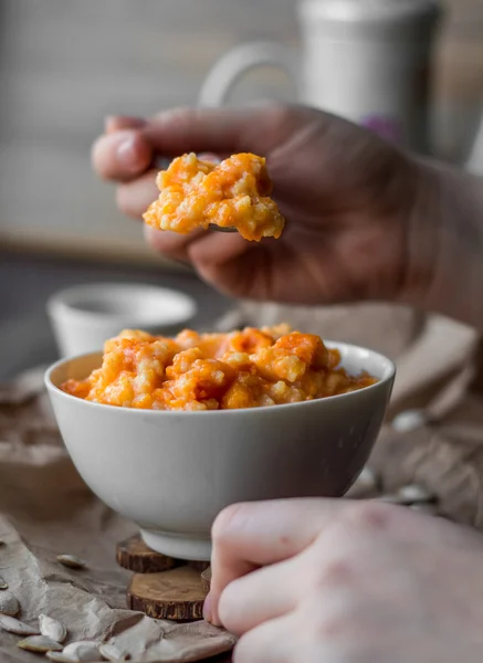 Eating pumpkin millet porridge with milk, hands, breakfast — Stock Image Eating pumpkin millet porridge with milk, hands, breakfast Stock Image