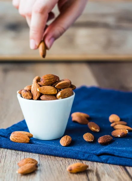 Eat nuts, almonds hands of white cup — Stock Photo, Image