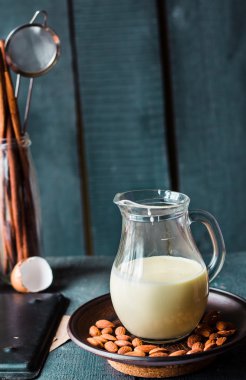 yoğunlaştırılmış süt bir sürahi cam, bir plaka üzerinde koyu badem