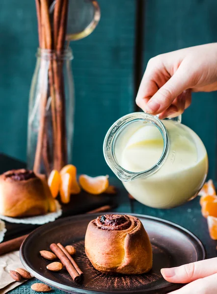 Cinnabon cinnamon rolls with cream sauce to pour, hands — Stock Photo, Image