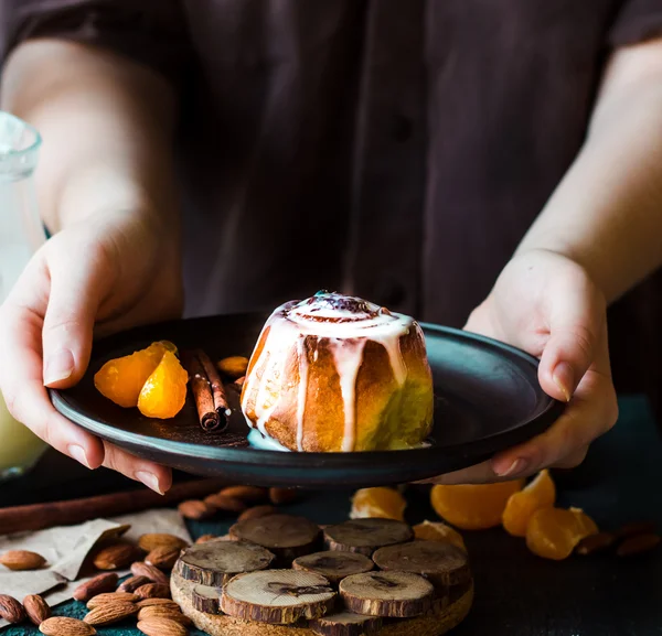 Handle Cinnabon cinnamon rolls and mandarin and cream sauce — Stock Photo, Image