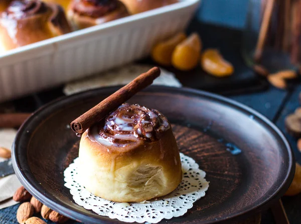 Cinnabon cinnamon rolls, almonds and mandarins on a dark plate — Stock Photo, Image